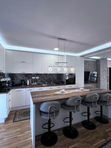 eine Küche mit weißen Schränken und eine Insel mit Barhockern in der Unterkunft Dudex Apartment in Sarajevo