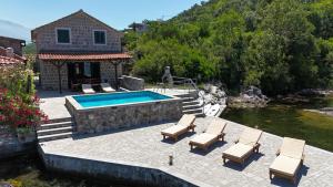 a swimming pool with lounge chairs and a house at Apartments Kovinic in Tivat