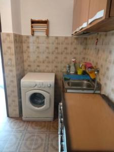eine kleine Küche mit einer Waschmaschine und einem Waschbecken in der Unterkunft La Casa Ottagonale! in Alba Adriatica