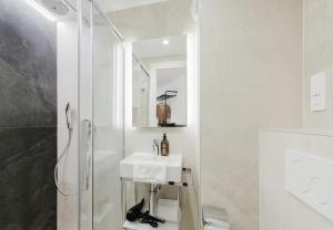 a white bathroom with a sink and a shower at Appart Hotel Neostelia in Annecy