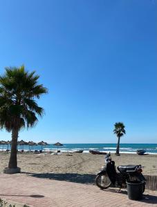 a motorcycle parked on a beach with palm trees at Guest House Bujtina ISMET GJELI in Kavajë +13 photos