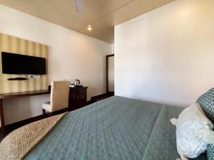 a bedroom with a bed and a chair and a television at Hotel Sunny Cot - Free Mall Shuttle and Parking in Mussoorie