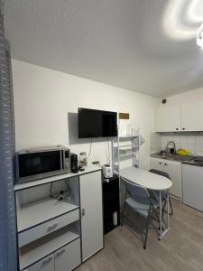 a small kitchen with a table and a microwave at Studio en RDC, climatisé in Lamalou-les-Bains