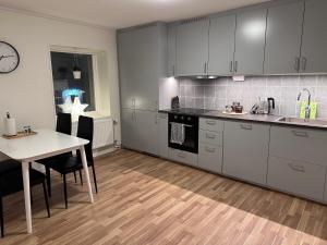 una cucina con armadi grigi, tavolo e sedie di Silverlägenheterna a Sala