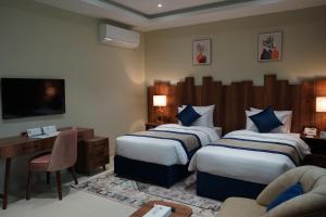 a hotel room with two beds and a desk at فندق ريان الجنادرية للشقق المخدومة Rayyan Al Janadriyah Hotel in Riyadh