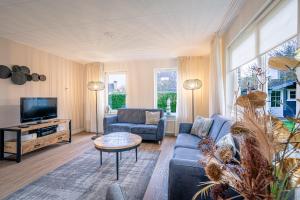 Una sala de estar con un sofá y un televisor. en Villapark Kamperfoelie 89, en De Koog