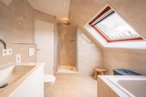Un baño con lavabo, inodoro y tragaluz. en Villapark Kamperfoelie 89, en De Koog 5 fotos más