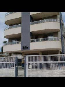 ein hohes Gebäude mit einem weißen Zaun davor in der Unterkunft Apartamento Só Alegria in Bombinhas