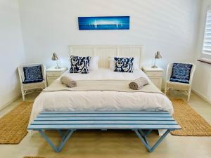 a bedroom with a bed with two chairs at Panorama Sea-View Apartment in Plettenberg Bay