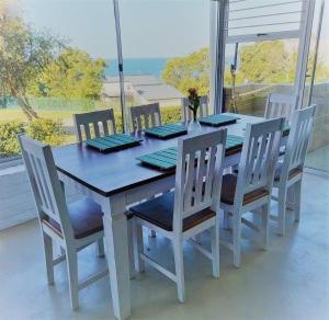 a dining room table and chairs with a view of the ocean at Panorama Sea-View Apartment in Plettenberg Bay