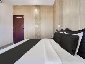 a bedroom with a black and white bed and a door at Hotel O Gp Homestay in Dehradun