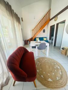 a living room with a red chair and a table at Bahia Beach- Duplex, plage privée, Netflix in Cayenne