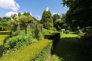 a garden with green bushes and a fence at Appartement dans une Villa de Prestige avec Étangs et Serre in Braine-lʼAlleud