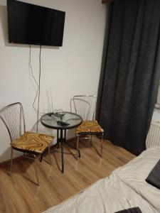 Habitación con mesa, 2 sillas y TV. en Ubytovanie Doro, en Prešov