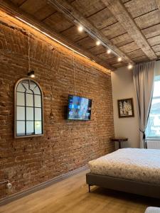 a bedroom with a brick wall with a bed and a tv at Elite apart on Shevchenko Avenue in Lviv