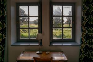 einen Tisch und zwei Fenster in einem Zimmer mit einem Tisch und einem Pferd in der Unterkunft Closerie de La Salière, gîte de charme et chambres d'hôtes, châteaux de la Loire, zoo de Beauval in Le Controis En Sologne