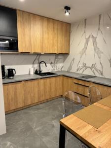 a kitchen with wooden cabinets and a sink and a table at Baltic Waves Resort Luksusowy apartamnet z basenem i parkingiem in Międzyzdroje