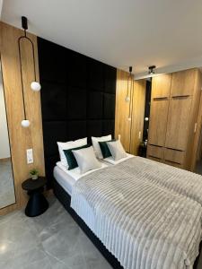 a bedroom with a large bed with a black headboard at Baltic Waves Resort Luksusowy apartamnet z basenem i parkingiem in Międzyzdroje +14 photos