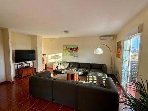 a living room with a couch and a television at A 5 minutos de la playa casa de vacaciones con piscina privada in Puerto de Mazarrón