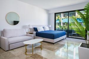a living room with a bed and a couch at Menesse Town Tower 202 condo in Playa del Carmen