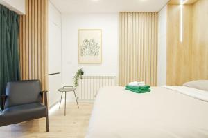 Un dormitorio con una cama blanca y una silla negra. en Designers Apartment - chic choice for the stay, en Iaşi