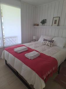 a bedroom with a large bed with towels on it at Balcón del Lago - Cabaña 1 in Maipo