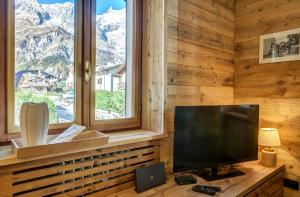 Una sala de estar con un televisor de pantalla plana y una ventana. en Casa Entreves - Ristrutturata con parcheggio, en Courmayeur
