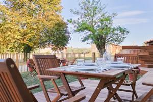 a wooden table and chairs on a wooden deck at La Maison des Champs in Cintegabelle