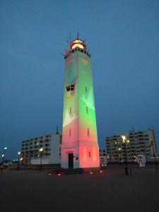 a lighthouse is lit up green and pink at ZeeBedStay in Noordwijk aan Zee