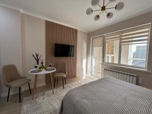 a bedroom with a bed and a table and a tv at Apart Complex Meridian из 10 отдельных апартаментов рядом с Арбатом in Almaty