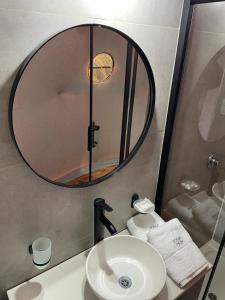 a bathroom with a sink and a round mirror at Domos Park in Mar de las Pampas