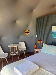 a bedroom with a bed and two chairs and a table at Domos Park in Mar de las Pampas +31 photos