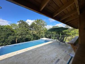 a swimming pool with an umbrella and a table and chairs at Villa RG in Jarabacoa