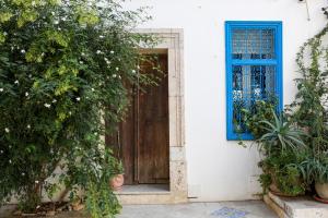 a wooden door with a blue window and plants at Typique maison in Dar Mimoun Bey