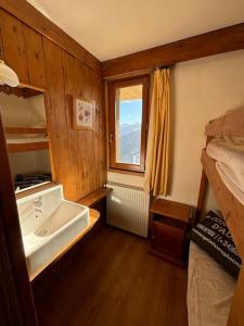 a bathroom with a sink and a bed and a window at Chalet de l'Ours - Pla d'Adet in Cadeilhan-Trachère