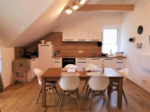 Tauplitz Panorama Apartment, 75qm, Balkon und Sauna في توبليتز: مطبخ مع طاولة خشبية ودواليب بيضاء