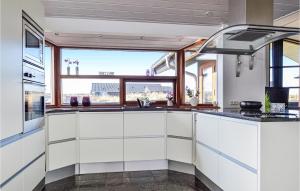 a kitchen with white cabinets and a large window at Holiday Home Arvidvej Hvide Sande Denm in Bjerregård