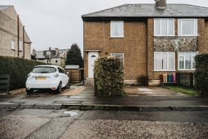 ein weißes Auto, das vor einem Backsteinhaus parkt in der Unterkunft Large bedroom, close to Airport and City Centre in Edinburgh