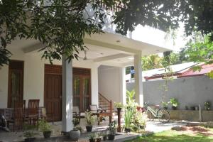 a house with a porch with chairs and a bike at Villa Wanderlust in Hikkaduwa