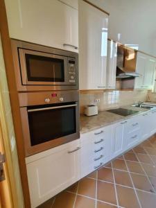 a kitchen with stainless steel appliances and white cabinets at Cantinho da Carminho in Amoreira