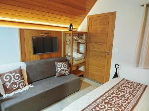 a living room with a couch and a flat screen tv at Chalé Sognare Uno in Santa Teresa