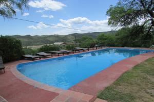 a large blue swimming pool with benches around it at Mirador del lago apart y cabañas- exclusivo adultos in Las Rabonas