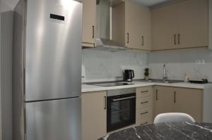 a stainless steel refrigerator in a kitchen with white cabinets at Trikala Escape House in Tríkala