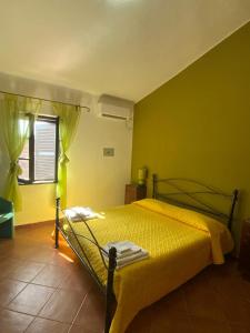 a bedroom with a bed with yellow walls and a window at Alghero - Grotte di Nettuno cortes in Santa Maria la Palma +74 photos