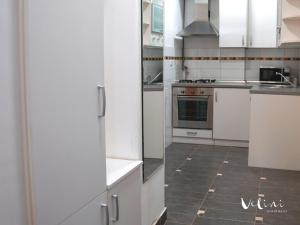 a kitchen with white cabinets and a tile floor at Apartment Velini in Zagreb