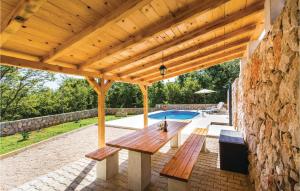 a patio with a wooden table and a stone wall at Awesome Home In Krk With Wifi in Risika