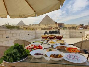 a table with bowls of food on it with the pyramids at Antique Pyramids Inn in Giza
