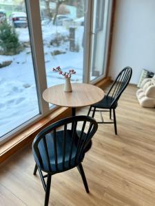 una mesa con dos sillas y un jarrón con flores. en Ostoja Pod Szrenicą, en Szklarska Poręba