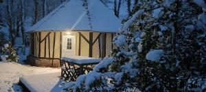 una cabaña cubierta de nieve con un banco frente a ella en Le manège terre et mer proche Etretat, en Gonneville-la-Mallet