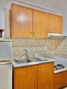 a kitchen with wooden cabinets and a sink at Marinos Studios and Apartments in Gialiskari